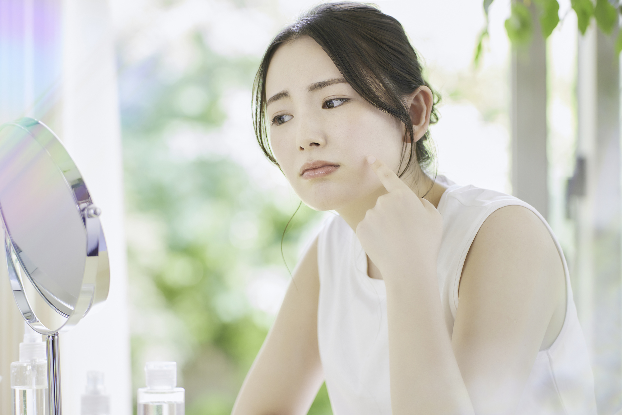 朝に鏡で肌をチェックする女性