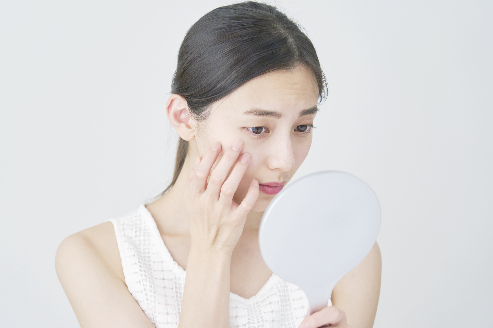 鏡で肌を確認する女性