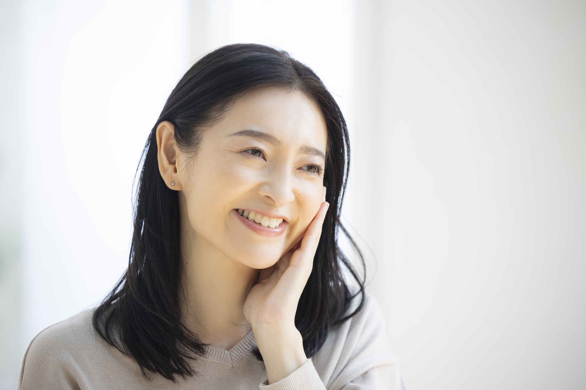 顔をタッチする女性の画像