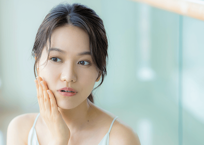 頬に手を当てて肌の状態を確かめる女性