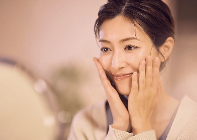 鏡の前で頬に手を添えて微笑む女性