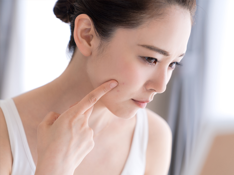 指で顔を触る女性